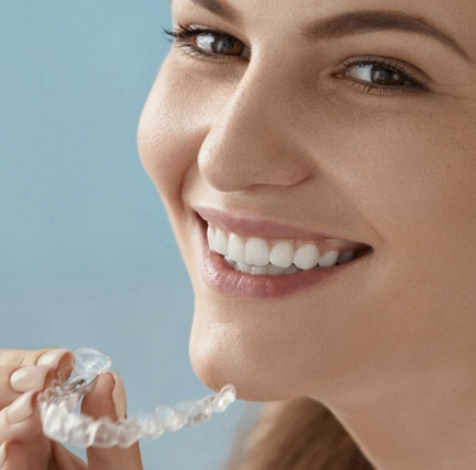 woman with white teeth holding whitening tray