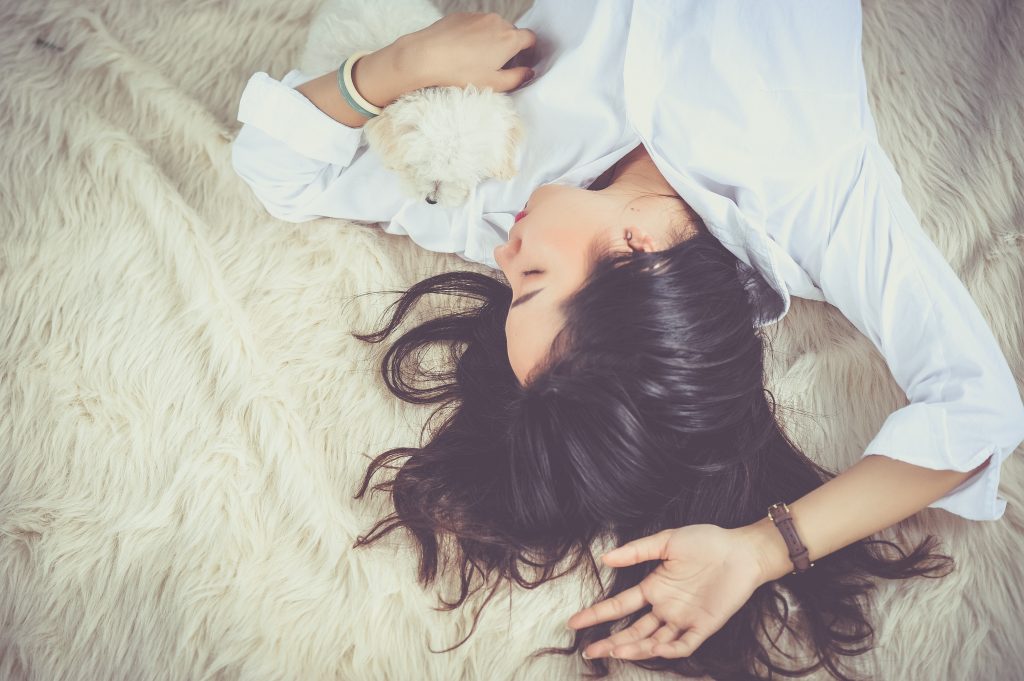 Woman sleeping on rug with a dog