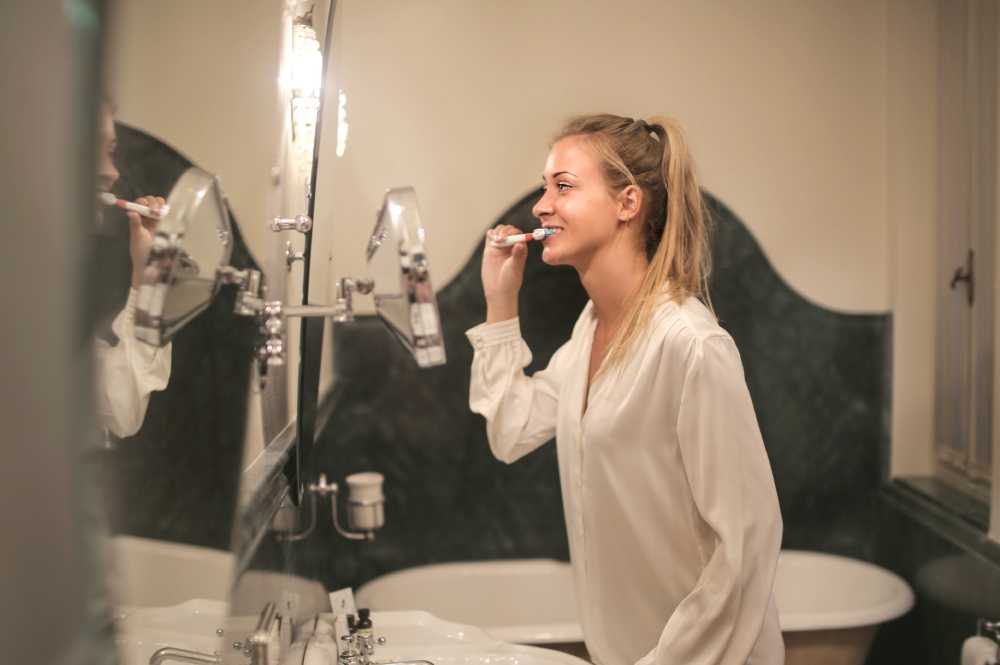 Woman looking in mirror brushing her teeth
