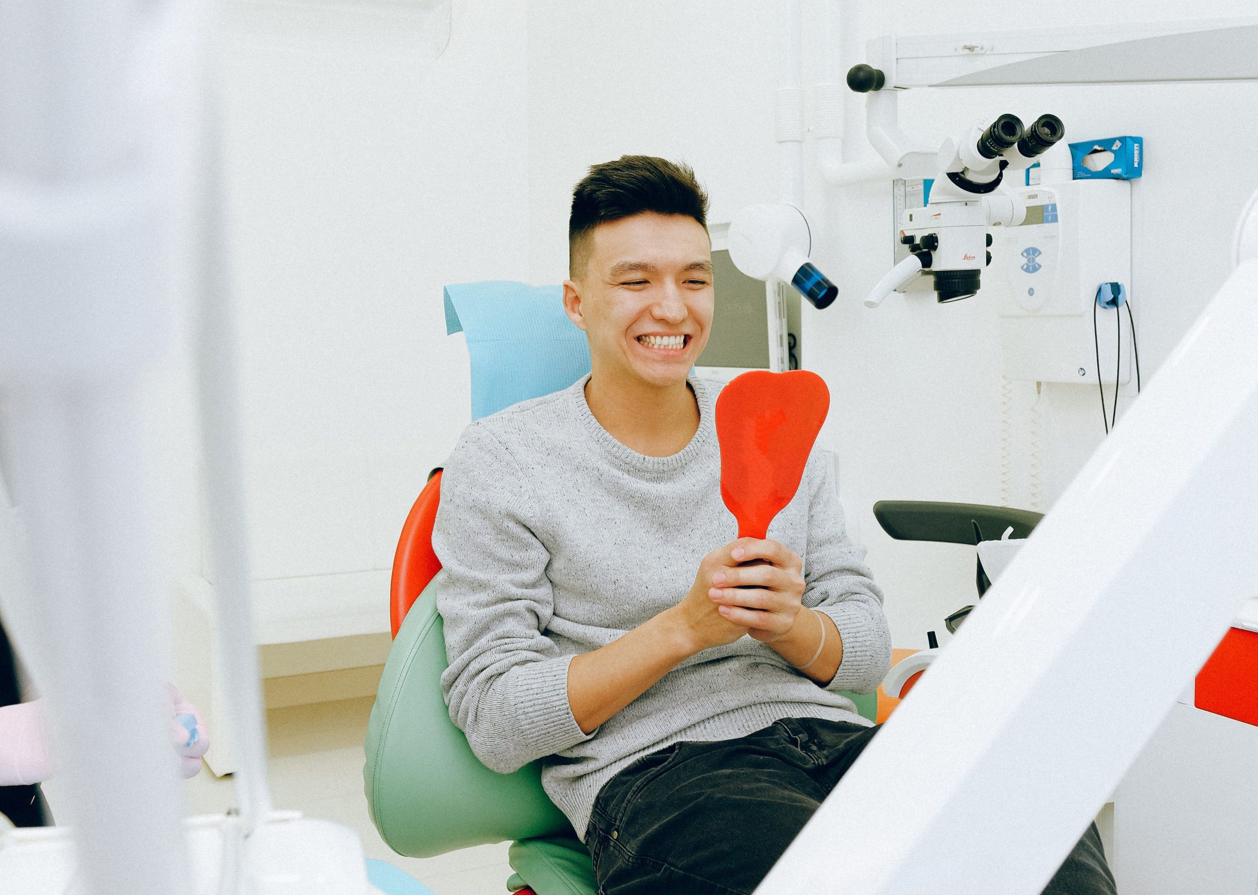 Man in dental chair looking at a mirror smiling