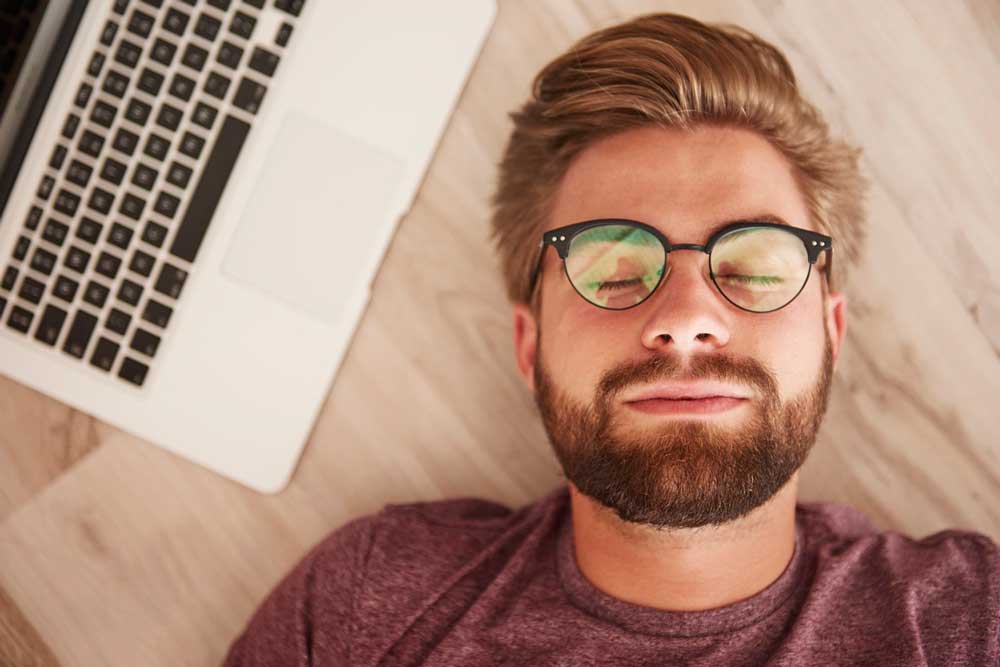 Man laying down on desk next to computer