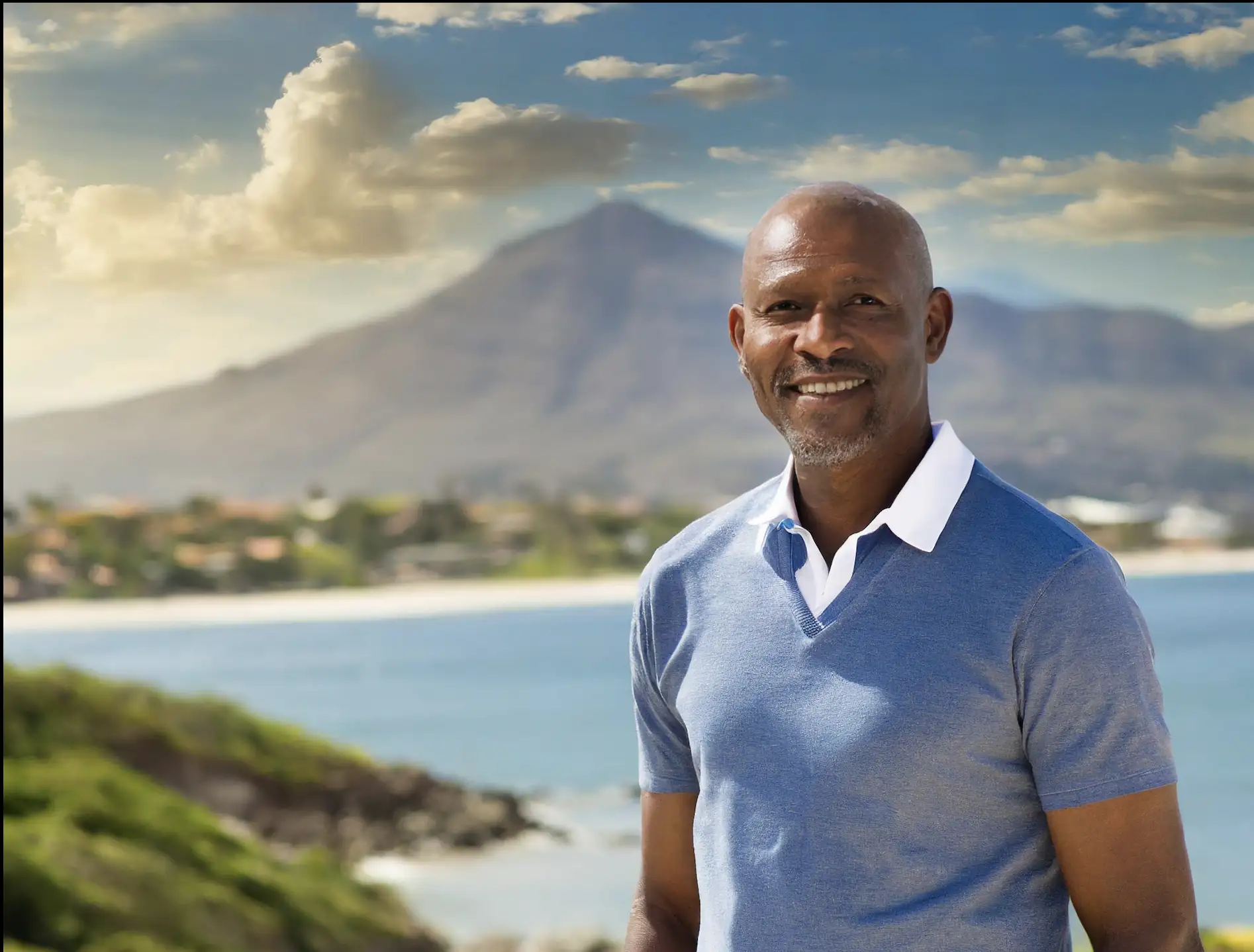 Older gentleman smiling in front of water and mountains